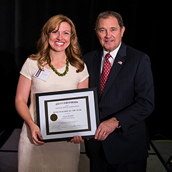 picture of a woman holding an award standing next to a dignitary